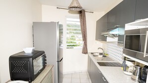 A compact kitchen with a microwave, toaster, refrigerator, and a sink.