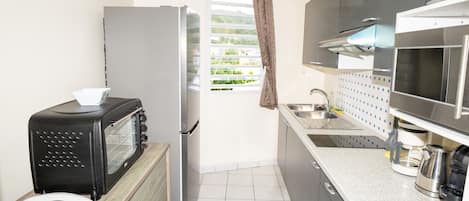 Cocina compacta con microondas, tostadora, refrigerador y lavamanos.