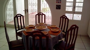 A dining area with a round table, six wooden chairs, and decorative plates. - Ideal for holidays (NABEUL)