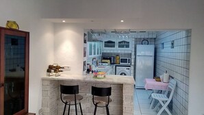 A compact kitchen with a bar area, a washing machine, and a refrigerator. - Ideal for holidays (NABEUL)