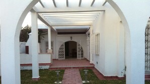A covered walkway with white pillars and red brick steps leading to a building entrance. - Ideal for holidays (NABEUL)