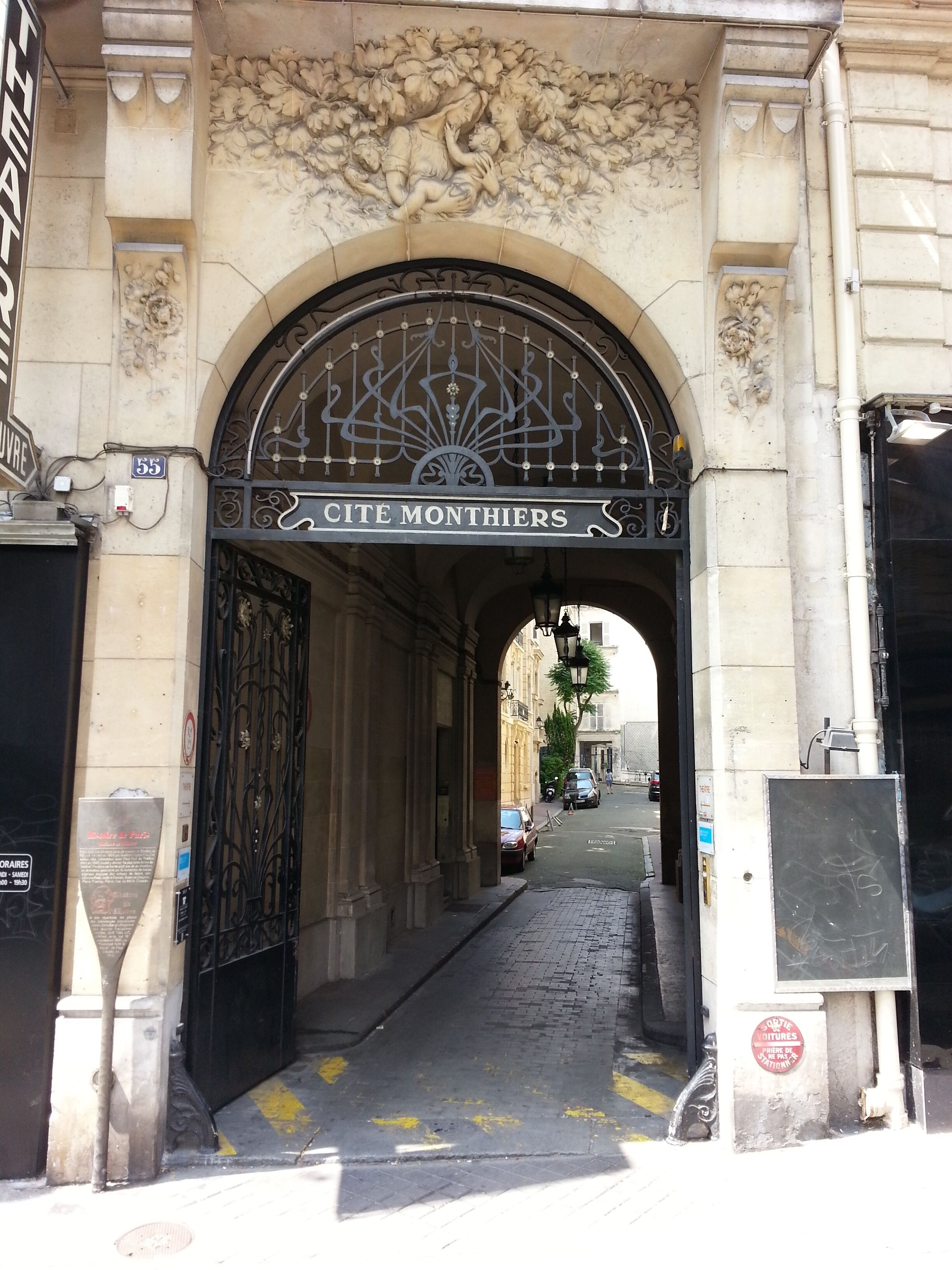 A stone archway with intricate carvings and a metal gate labeled "CITE MONTHERS".
