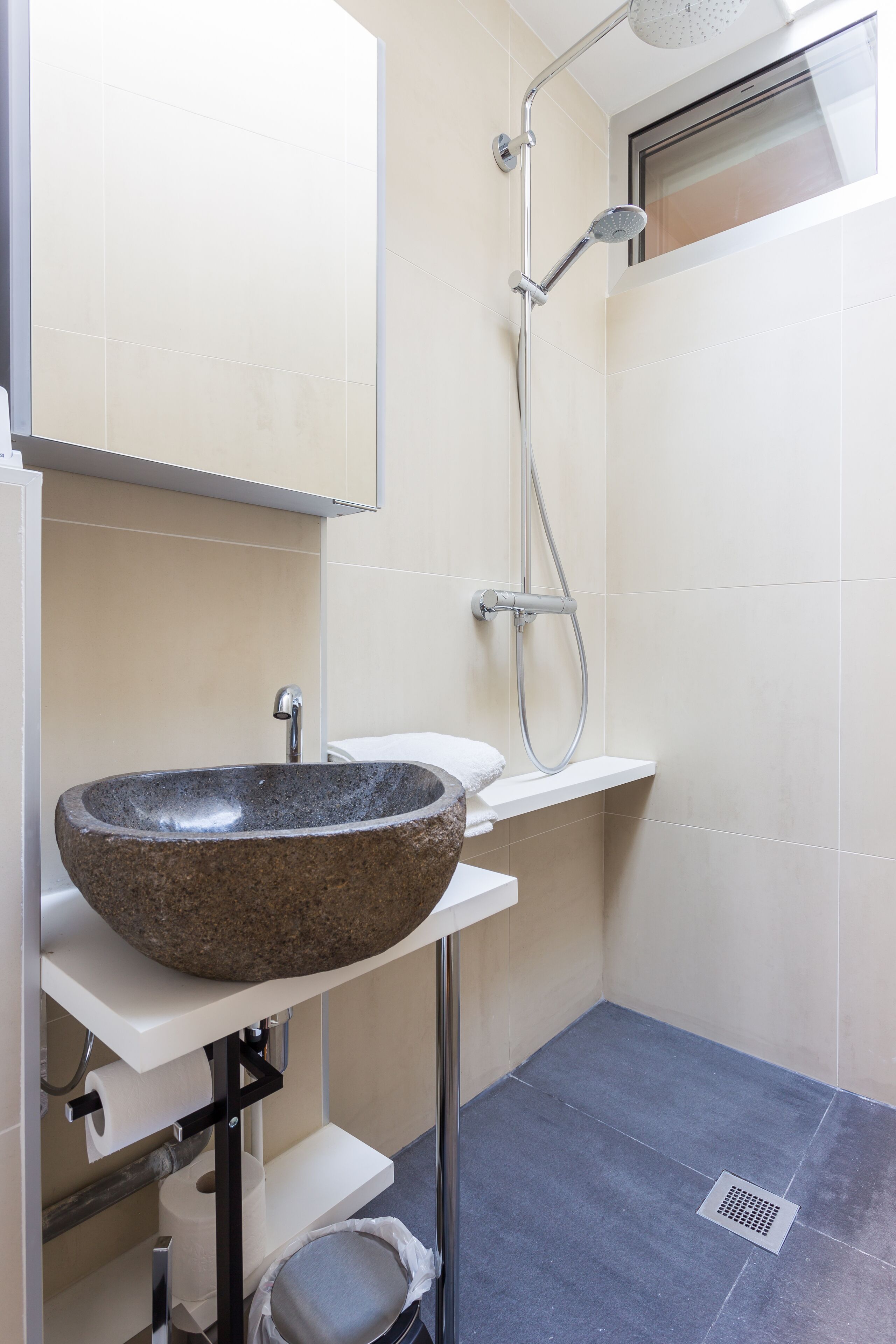 A bathroom with a stone sink, a shower, and a toilet.