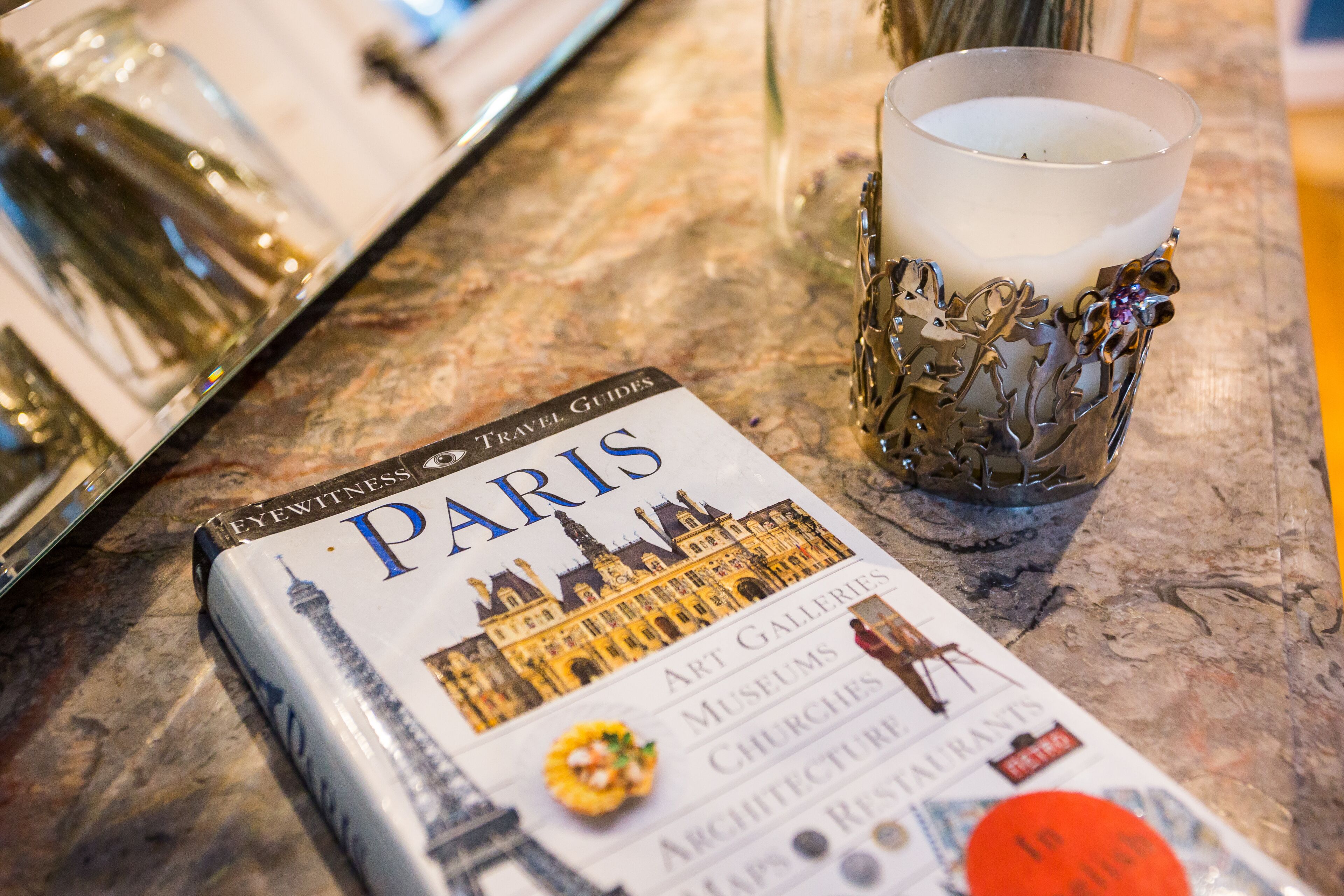 Una guía de viaje titulada 'PARIS' con un mapa de la ciudad, una vela y un vaso decorativo.