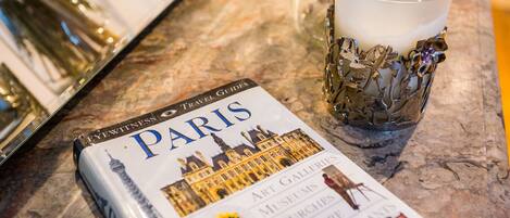 Una guía de viaje titulada 'PARIS' con un mapa de la ciudad, una vela y un vaso decorativo.