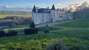 Un edificio grande e histórico con múltiples torres y un césped bien cuidado al frente.