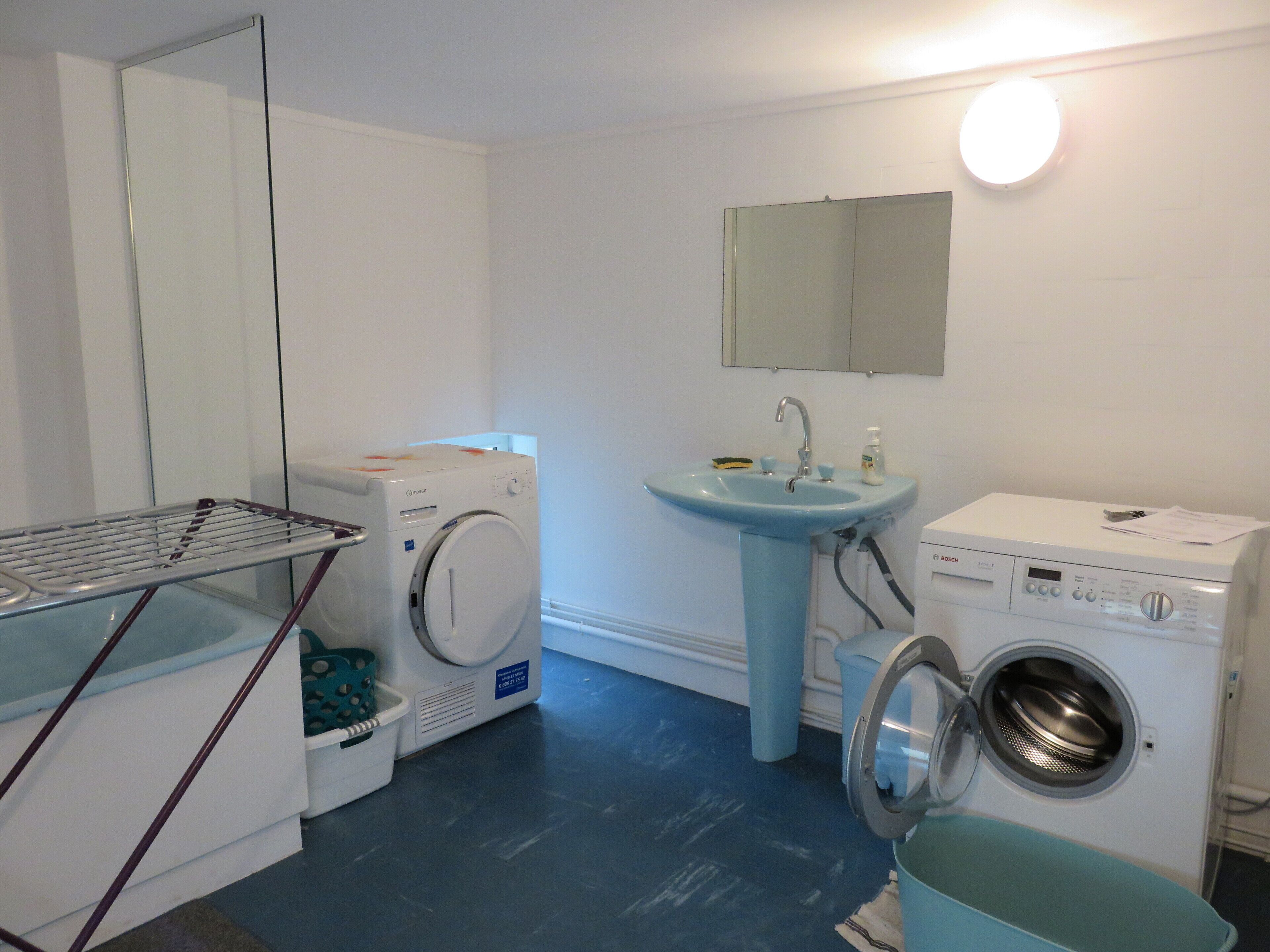 A laundry room with a washing machine, dryer, sink, and mirror.