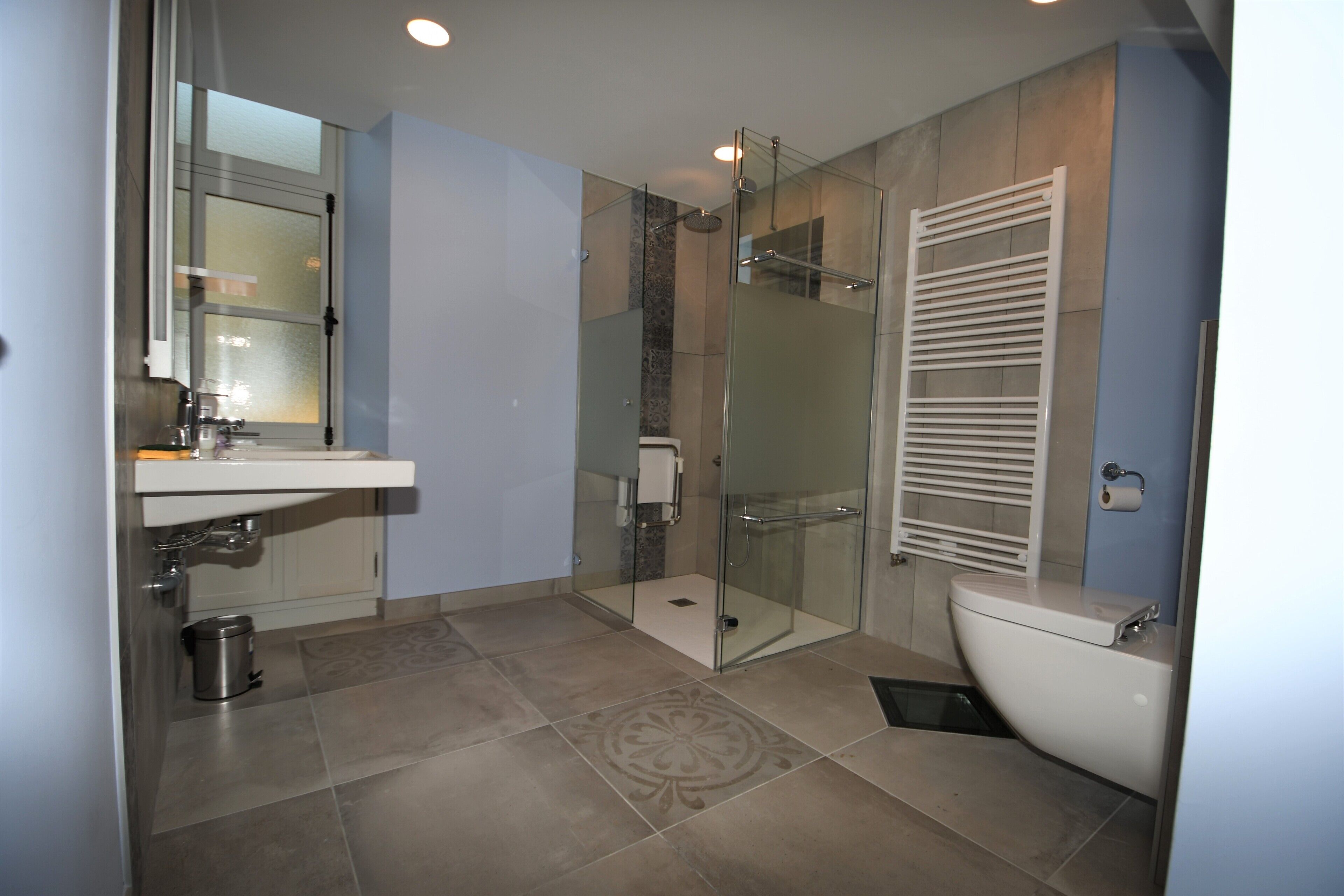 A modern bathroom with a glass-enclosed shower, a white sink, and a toilet.