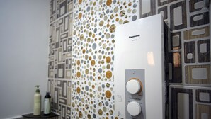 Casa de banho com parede estampada, um aquecedor Panasonic e uma prateleira com artigos de higiene pessoal.