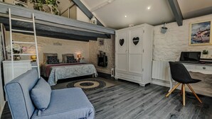 Une chambre compacte avec un lit en mezzanine, un bureau et une chaise.