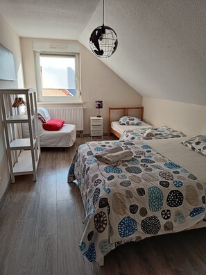 A bedroom with a bunk bed, a daybed, a radiator, a hanging light fixture, and a window with a view. - Large 3 room apartment of 85m2 (BISCHHEIM)
