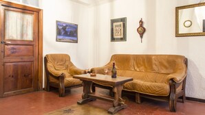 A room with a wooden door, two leather sofas, a wooden coffee table, and a patterned rug. - Apartment in the heart of the village (Puget-Théniers)