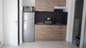 Una cocina compacta equipada con refrigerador, microondas y cafetera.