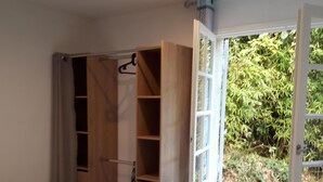 Un dormitorio con cama, armario de madera y ventana con vistas a la vegetación.