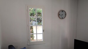 Una sala de estar con sofá, una mesita, un televisor y una ventana con vistas a zonas verdes.