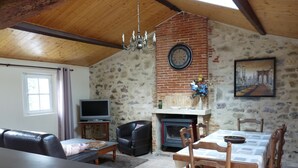 Una sala de estar con chimenea, televisor, mesa de comedor con sillas y sofá.