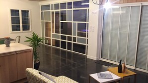 Et moderne interiør med sofa, et lille bord, en potteplante og en skydedør, der fører til en balkon.