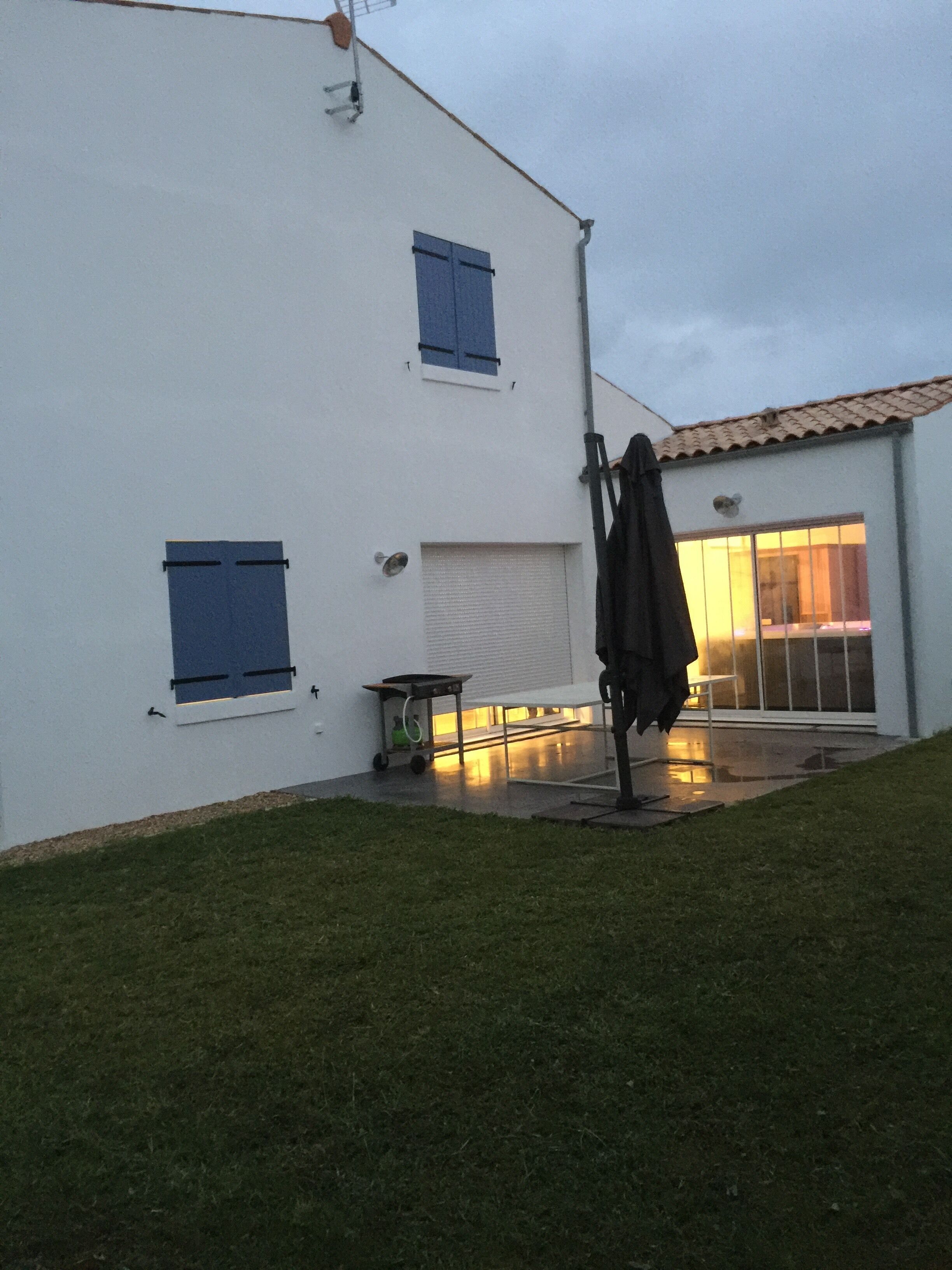 Un edificio blanco con contraventanas azules, una puerta de garaje y un porche cubierto.