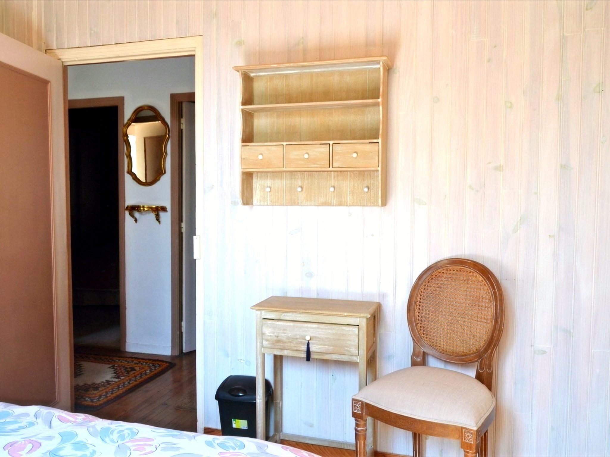 Une pièce comprenant un lit, une chaise, une petite table, un miroir et une armoire.