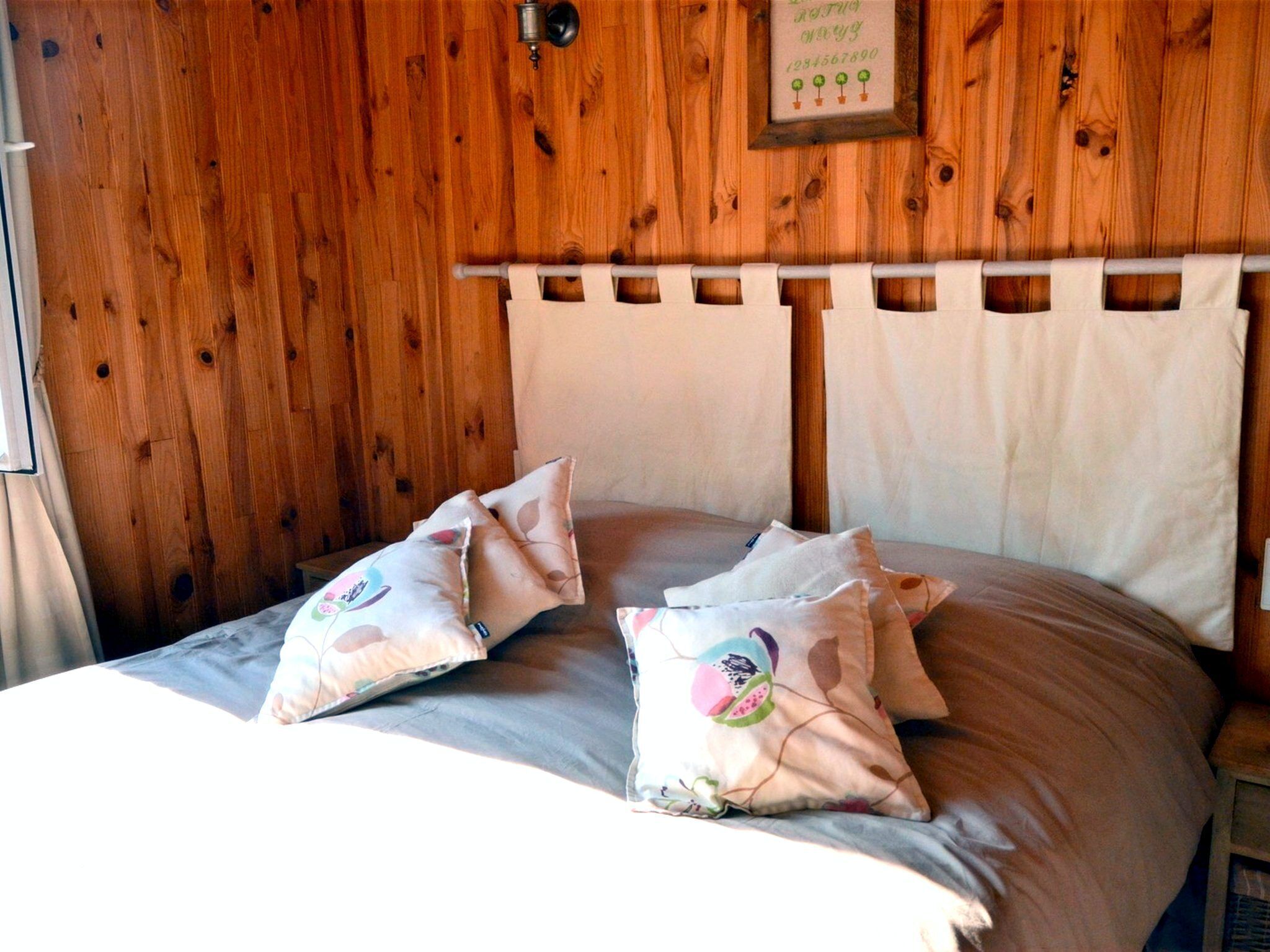 A wooden-paneled room with a bed, pillows, and a framed sign on the wall.