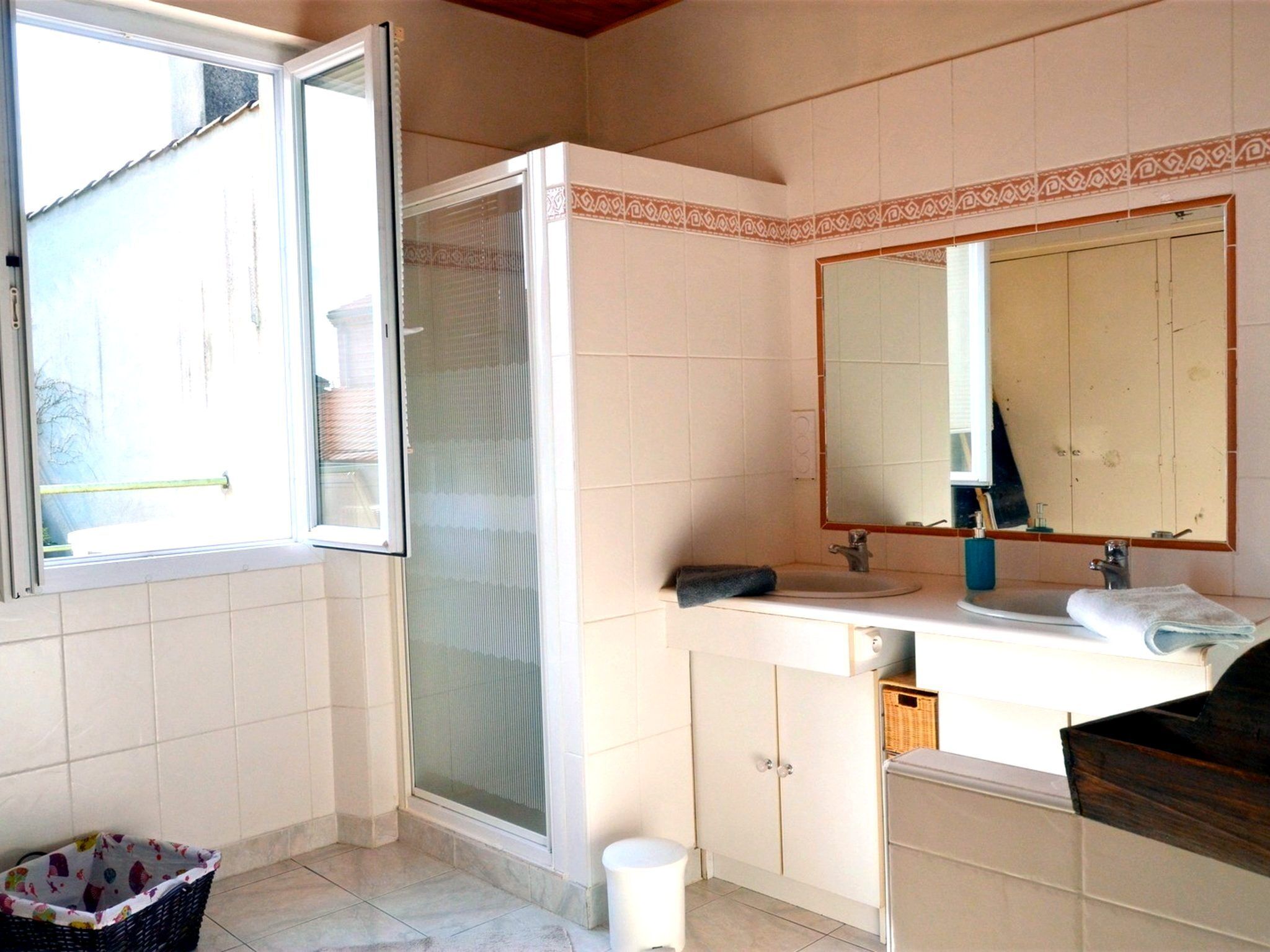 Une salle de bain avec une douche, un lavabo, un miroir et une fenêtre.