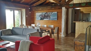 Een gezellig interieur van een chalet met een houten eethoek, een bank en een keuken.