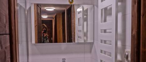Ein Badezimmer mit einem weißen Waschbecken, einem dunkelblauen Schrank und einem Spiegel darüber.