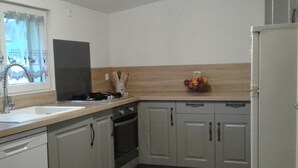 Una cocina con armarios blancos, estufa, fregadero y refrigerador.