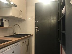 Et køkken med opvaskemaskine, vask og en sort dør.