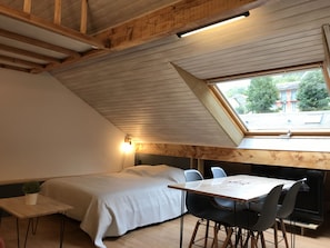 A small, cozy room with a sloped ceiling, a skylight, a bed, a table, and chairs. - Joli studio 4P entre télécabine et Commerces (Cauterets)