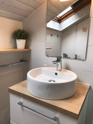 A bathroom with a round white sink, a mirror, a potted plant, and wooden shelves. - Joli studio 4P entre télécabine et Commerces (Cauterets)