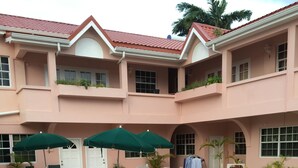 A poolside area with lounge chairs, umbrellas, and a tiled patio. - Your Home Away From Home (Rodney Bay)