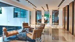 Eine moderne Lobby mit Glaswänden, Ledersofas und einem polierten Boden.