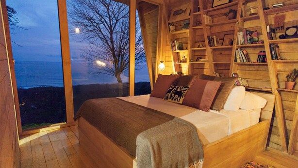 Un dormitorio acogedor con una cama grande, estanterías de madera y vistas al mar.