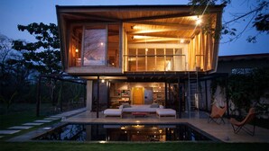 Una casa moderna de dos plantas con una terraza grande, una piscina y un comedor.