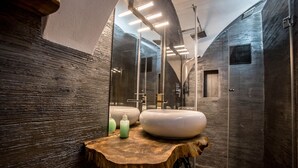 Een moderne badkamer met een houten wastafelmeubel, twee wastafels en een grote spiegel.