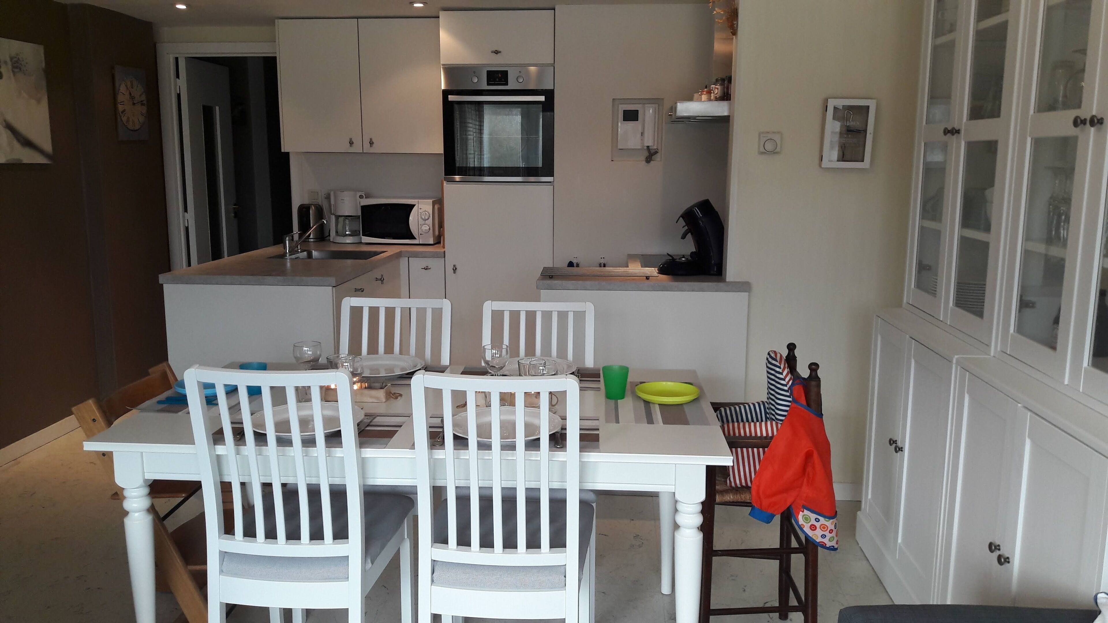 A compact kitchen with a dining area, featuring a microwave, oven, and sink.