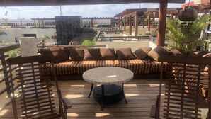A wooden deck with a round table and a striped sofa under a pergola. - Aldea Thai Penthouse  2br big private roof top & private pool by oceanfront  (Playa del Carmen)