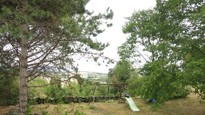 A rustic outdoor area with a wooden swing set, a green slide, and a stone wall. - Vacation rental for 3 people, 1 bedroom, pool, nature and peace and quiet guaranteed (Laurac)