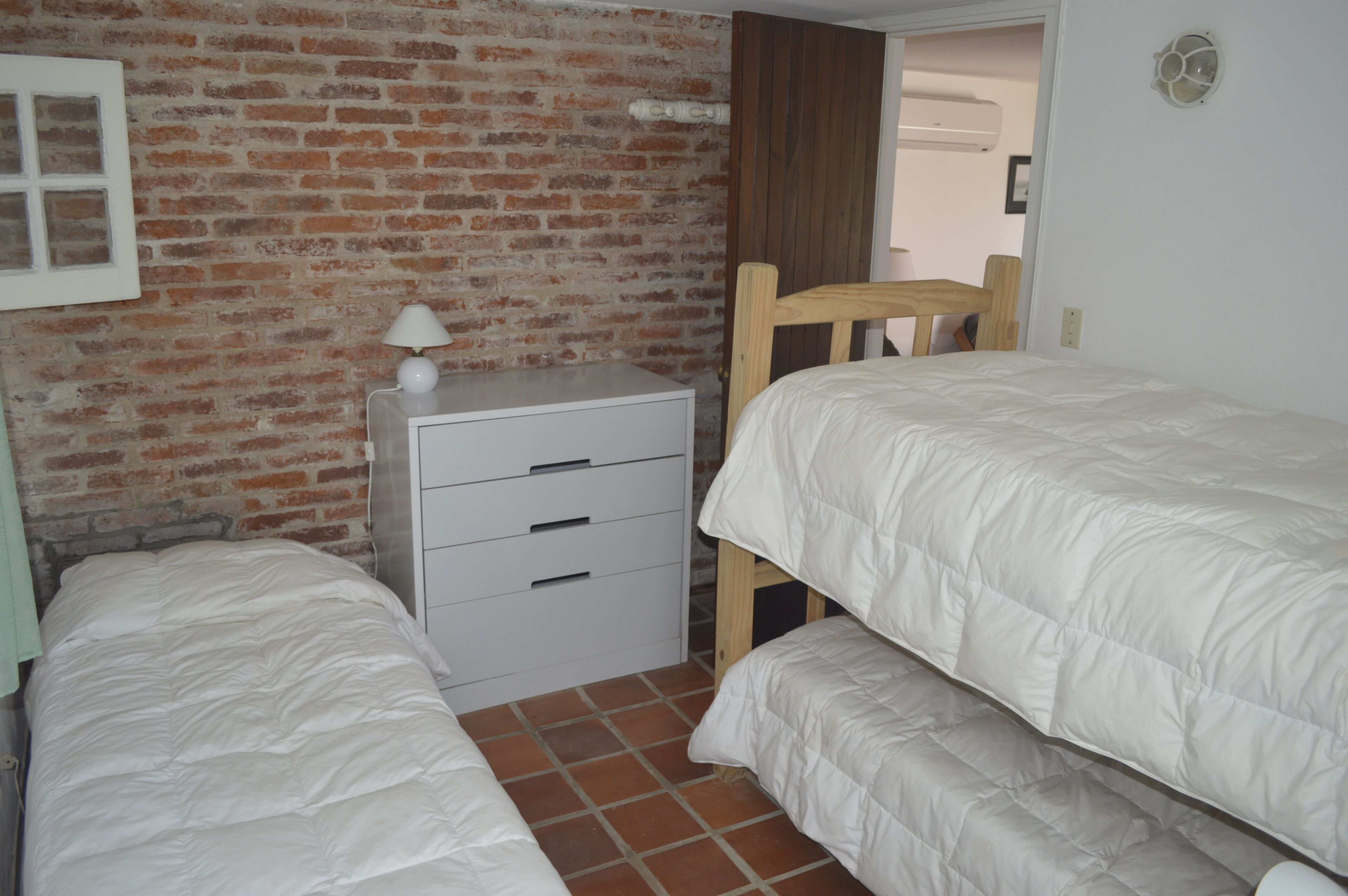 Une chambre avec deux lits, une table de chevet et un mur en briques.