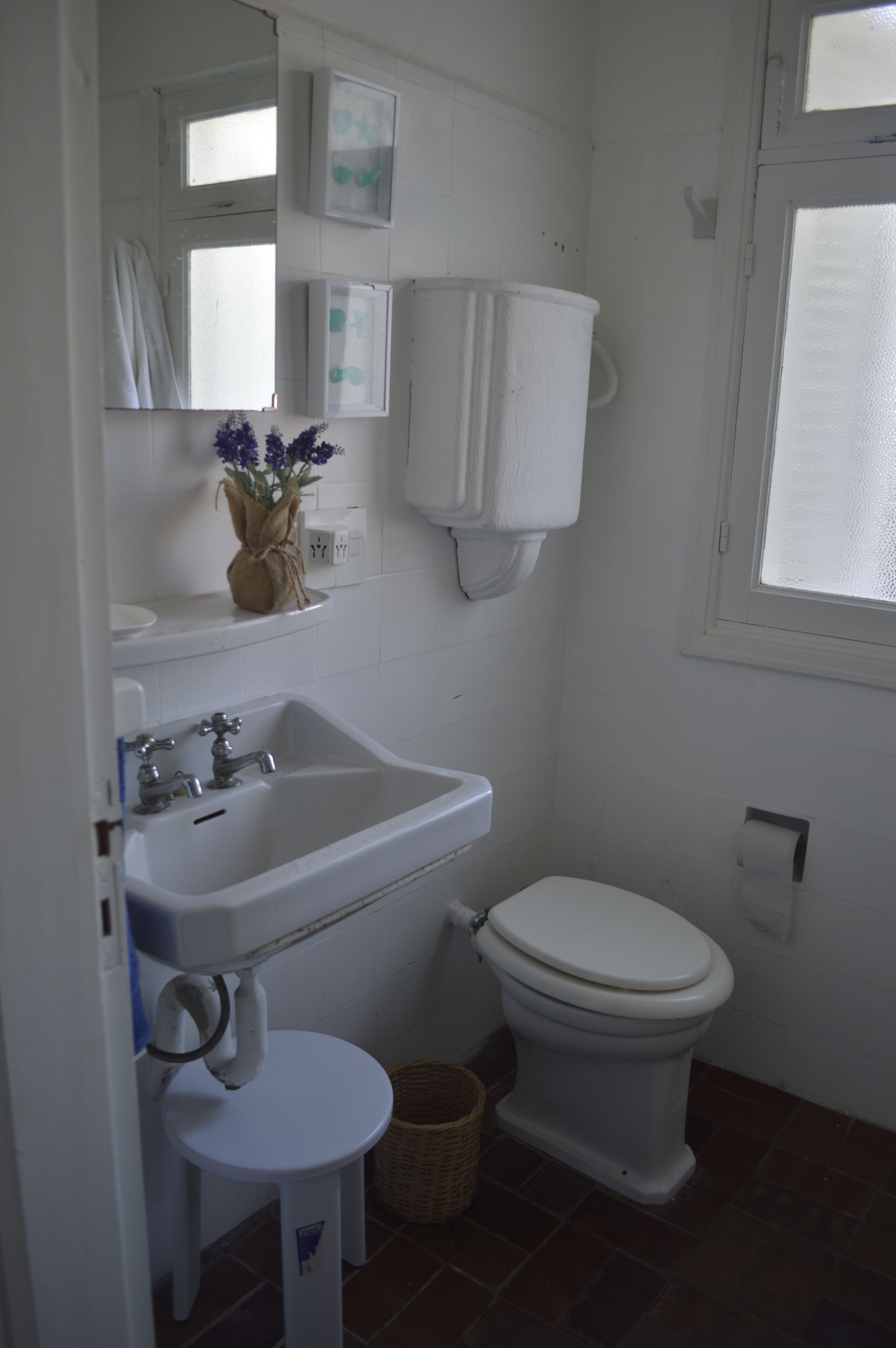 Ein Badezimmer mit Waschbecken, Toilette, Spiegel und kleinem Fenster.