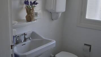 Ein Badezimmer mit Waschbecken, Toilette, Spiegel und kleinem Fenster.