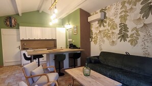 A compact living space with a kitchenette, a sofa, a dining table, and a patterned wall. - Air-conditioned gîte in Provence near Avignon, Arles, Saint Rémy de Provence, Nîmes  (Boulbon)
