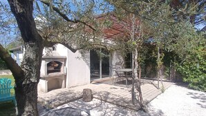 A patio area with a barbecue grill, outdoor seating, and a view of a house. - Air-conditioned gîte in Provence near Avignon, Arles, Saint Rémy de Provence, Nîmes  (Boulbon)