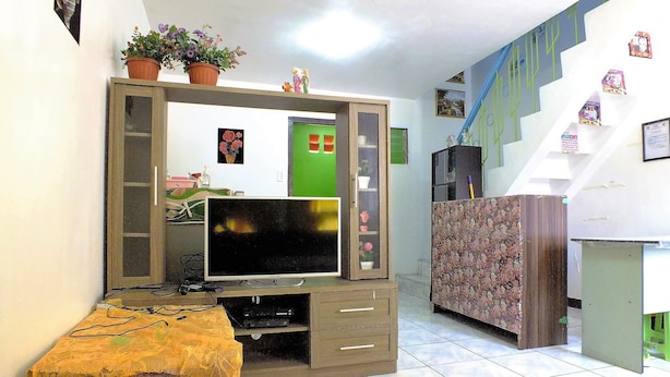 A living room with a TV, entertainment unit, and a staircase.