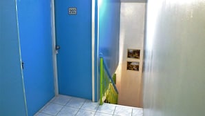 A blue door with the number 202, a green handrail, and a tiled floor.