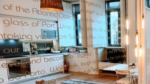 Una cocina moderna con una isla central, una lámpara colgante y vistas al océano Atlántico a través de un muro de cristal.
