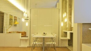 Un interior moderno con comedor, muebles blancos y lámparas colgantes.