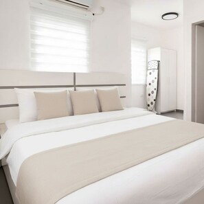 A hotel room with a large bed, a wardrobe, and a ceiling fan.