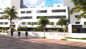 A modern building with multiple floors, large windows, and a flat roof. - Playa del Carmen in the Riviera Maya Exclusive Condo w/ golf course & beach club (Playa del Carmen)